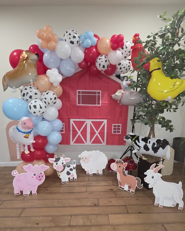 Farm-themed birthday setup with a red barn backdrop and animal balloon garland