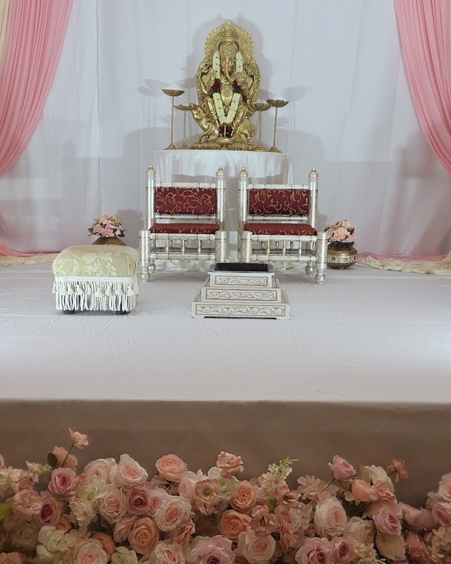 Gold idol on a cream dais with silver seating and a blush rose garland